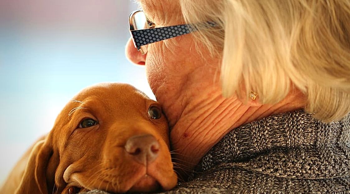 Personne âgée avec un chien sur l'épaule